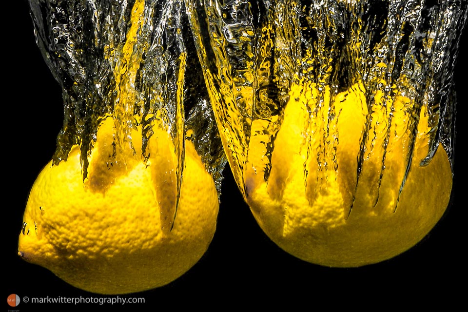 Two Lemons splashing into Water close up